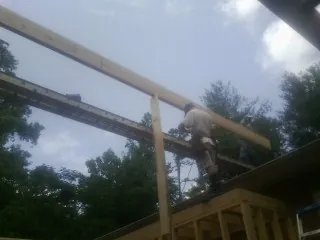 Carpenter setting a ridge beam over a new addition frame — Ice Dam Removal by Roofing Brothers in Floral Park