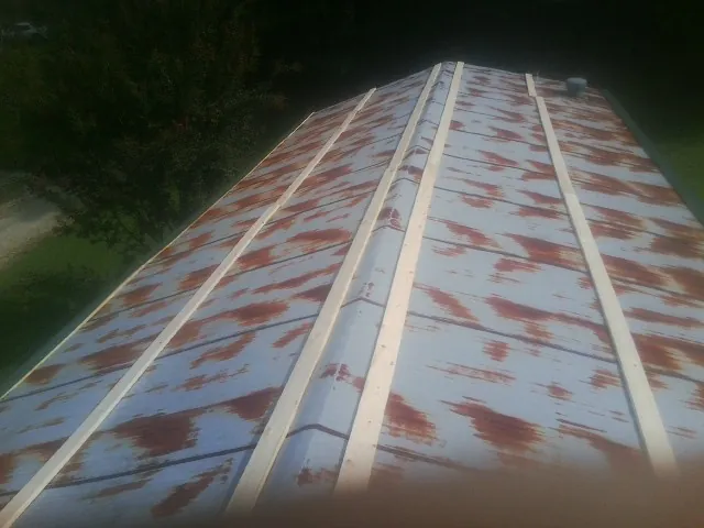 Rusted metal roof panels with new wood purlins before replacement — Storm Damage Roof Repair in Floral Park by Roofing Brothers