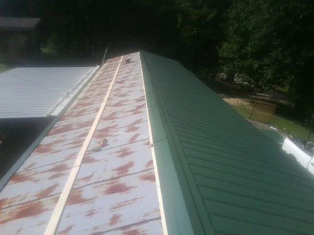 Old rusted panels beside newly installed green metal roofing — Wind Damage Roof Repair by Roofing Brothers in Floral Park