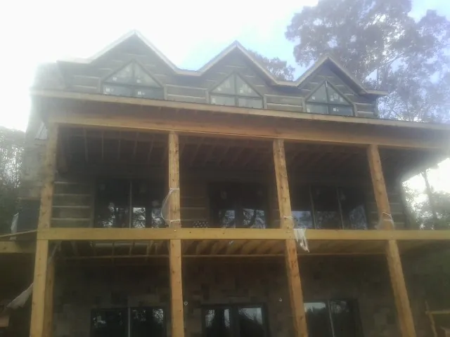 Dormers and porch framing on a large log home under construction — Roof Coating work by our crew in Floral Park