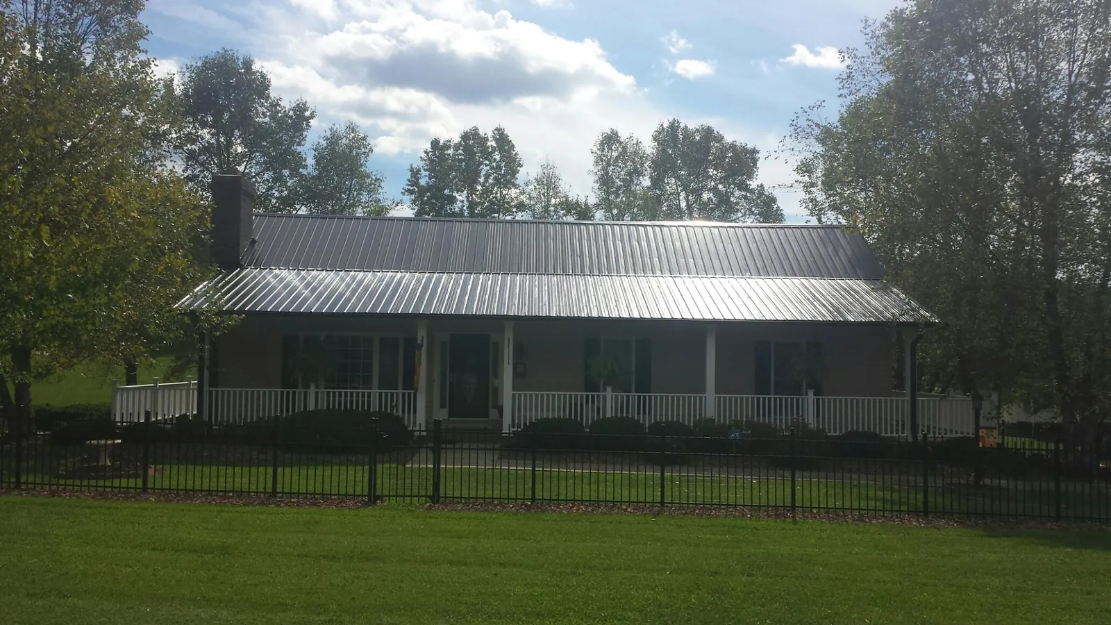Gray metal roof on a brick ranch with a full width front porch — Gutter Guard Installation work by our crew in Floral Park