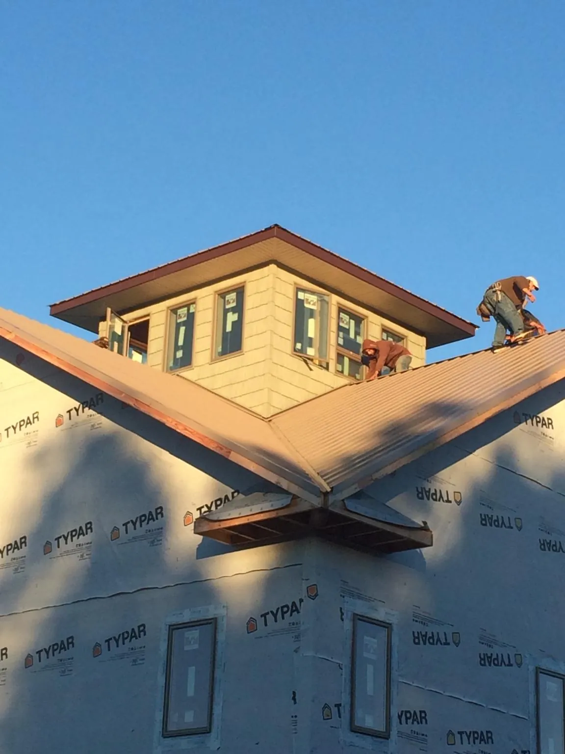 Roofers working around a rooftop cupola on a new metal roof at sunset — Roof Waterproofing in Floral Park by Roofing Brothers